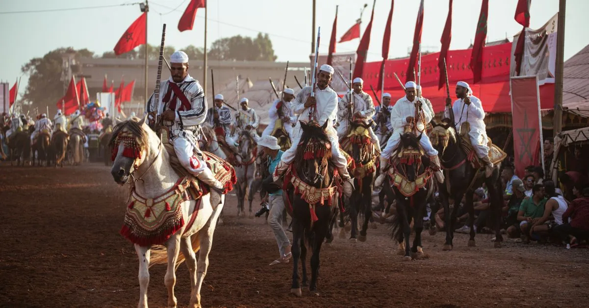 A colorful Fantasia event in Morocco featuring riders on horses in traditional attire, highlighting Moroccan culture.
