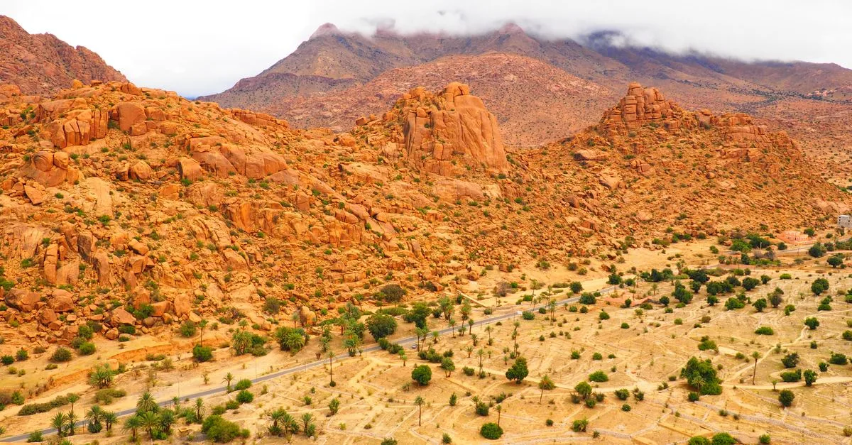 Aerial view of the vibrant red sandstone hills in Tafraout, Morocco, showcasing a dramatic desert landscape.