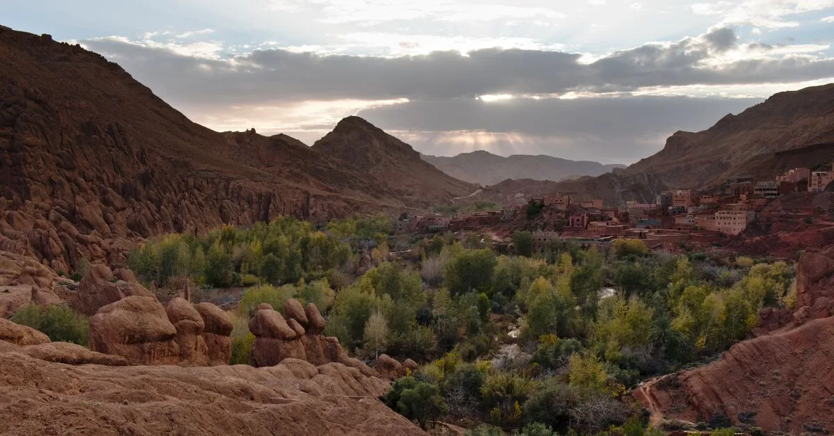 Beautiful valley in Morocco with lush greenery and rocky mountains under a twilight sky.