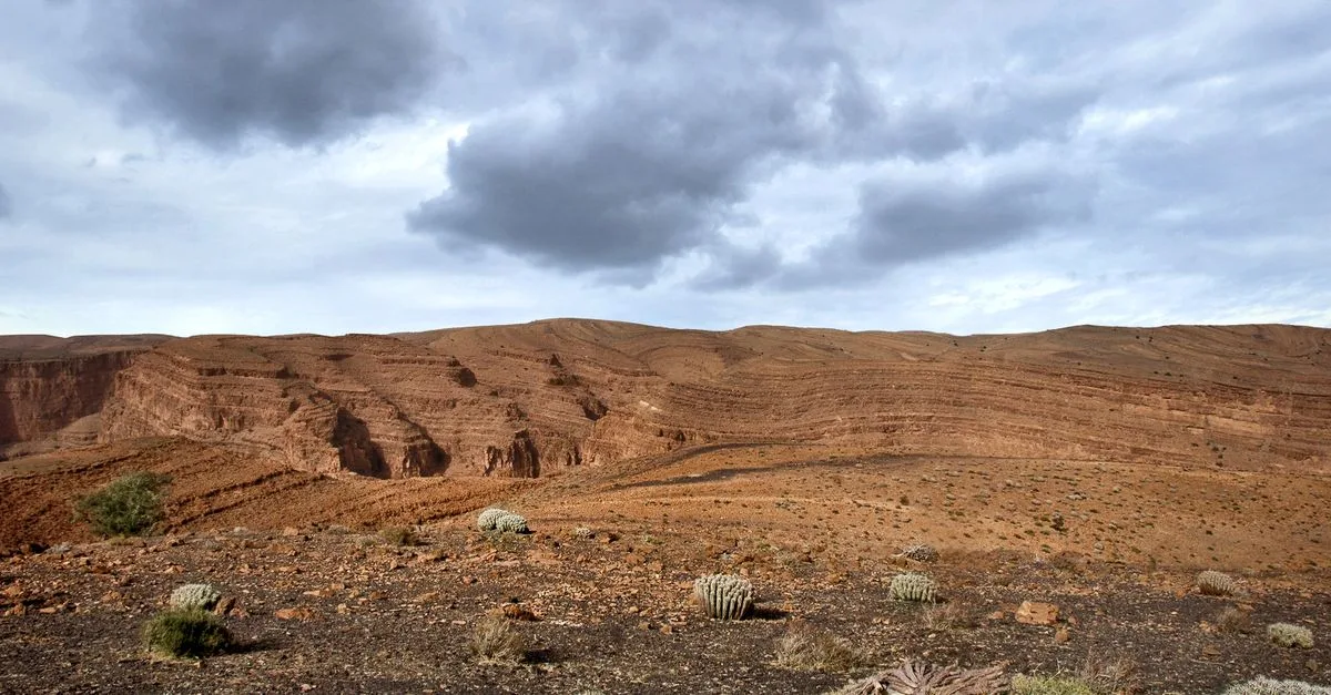 Explore the stunning arid landscape of Souss-Massa, Morocco with dramatic clouds and desert terrain.