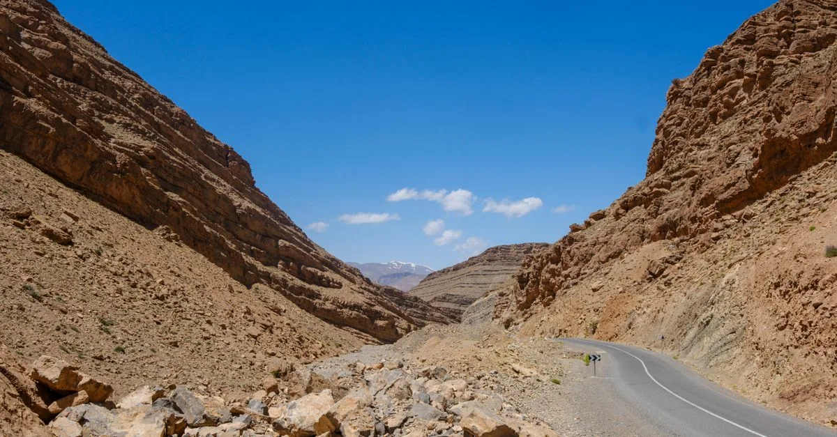 A breathtaking view of a winding road through the rocky Atlas Mountains under a clear blue sky in Morocco.