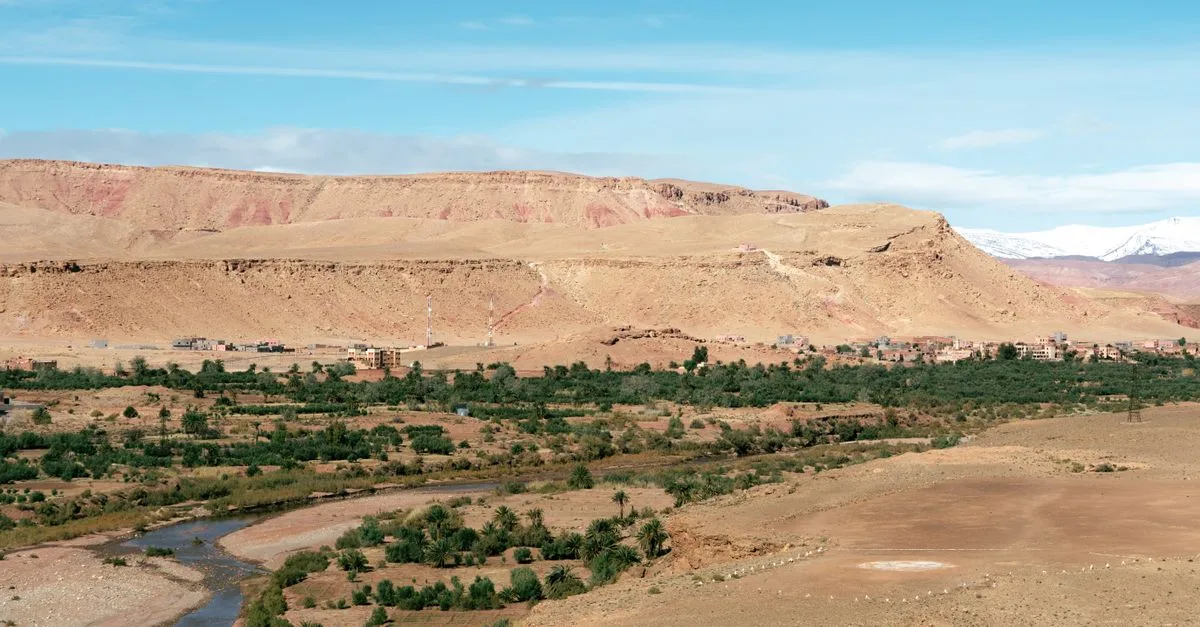 Stunning panorama of a Moroccan desert landscape with a winding river and distant mountains.