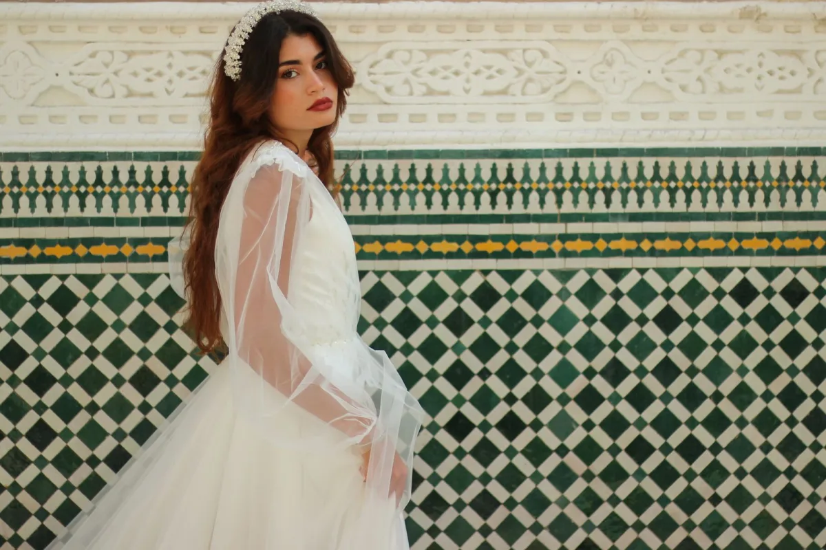 Mariée en robe de dentelle devant un décor traditionnel marocain à Marrakech.