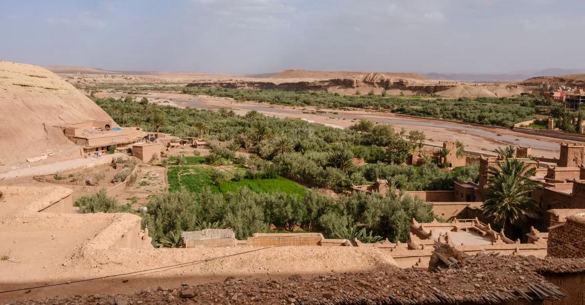 Explore the lush green valley against the backdrop of the majestic Atlas Mountains in Morocco.