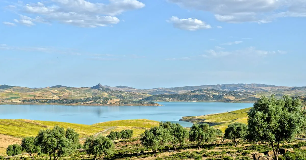 Peaceful landscape of Taounate with trees and lake under blue skies.