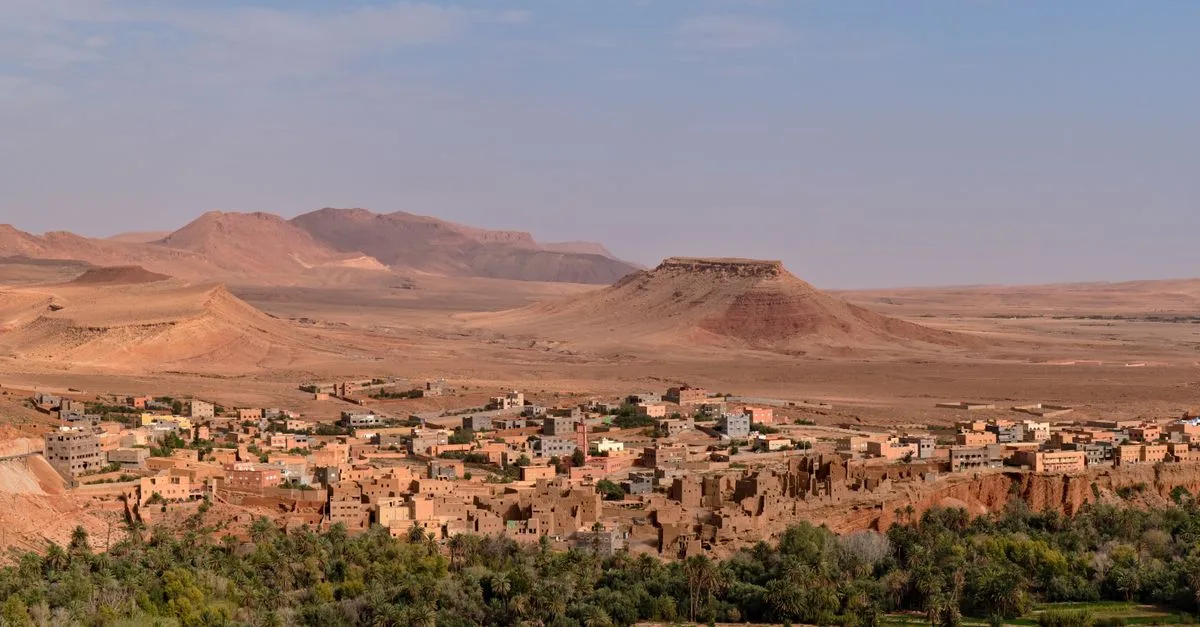 Aerial view of a traditional Moroccan town in a desert landscape with mountains.