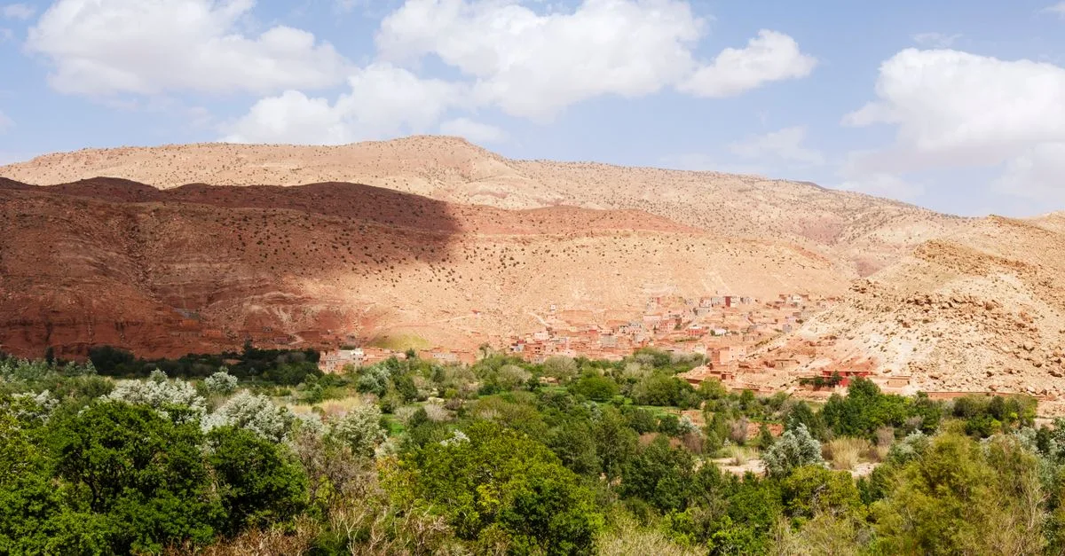 Stunning view of lush valley and clay-built village at the foot of Atlas Mountains in Morocco.