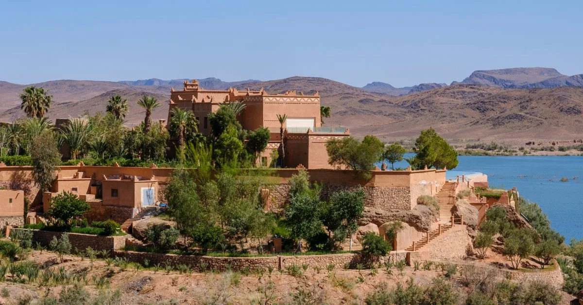 Stunning traditional Moroccan architecture overlooking Ouarzazate Lake with mountainous backdrop.