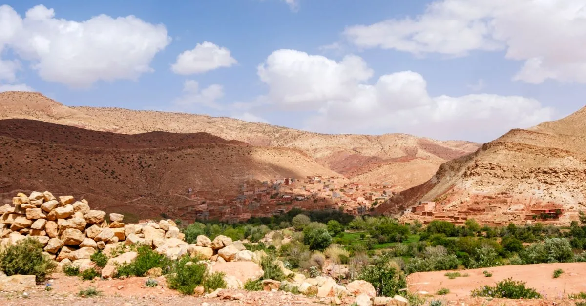 Scenic landscape of the Atlas Mountains with a traditional village under a vibrant sky in Morocco.